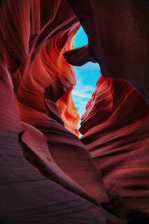 Light reaches Antelope Canyon, casting warm magenta and red hues on the sandstone, while shadows emphasize the canyon's eroded, winding form.