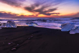 broken chunks of ice on black sand beach at sunrise in Iceland on the south coast.