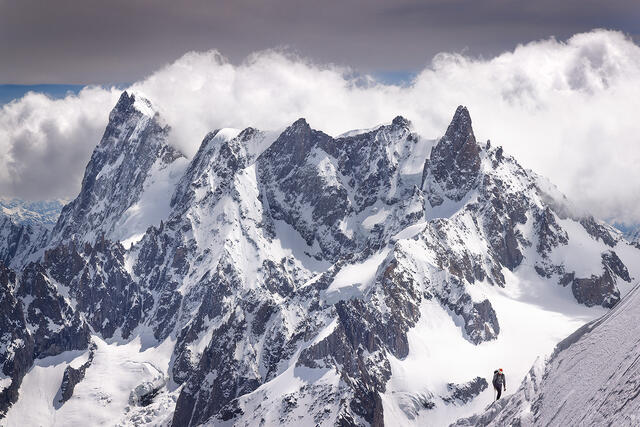 Mont Blanc with climber on snow ridge and dramatic jagged peaks, French Alps France