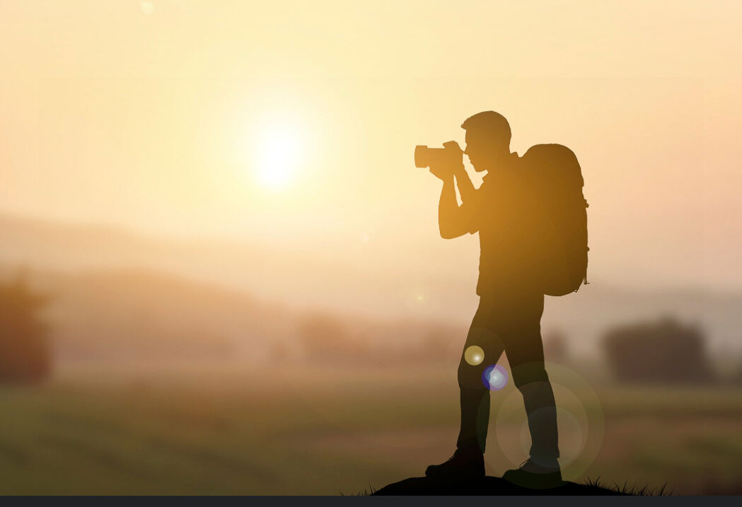 Photographer shooting the golden hour light at sunset in an open field.