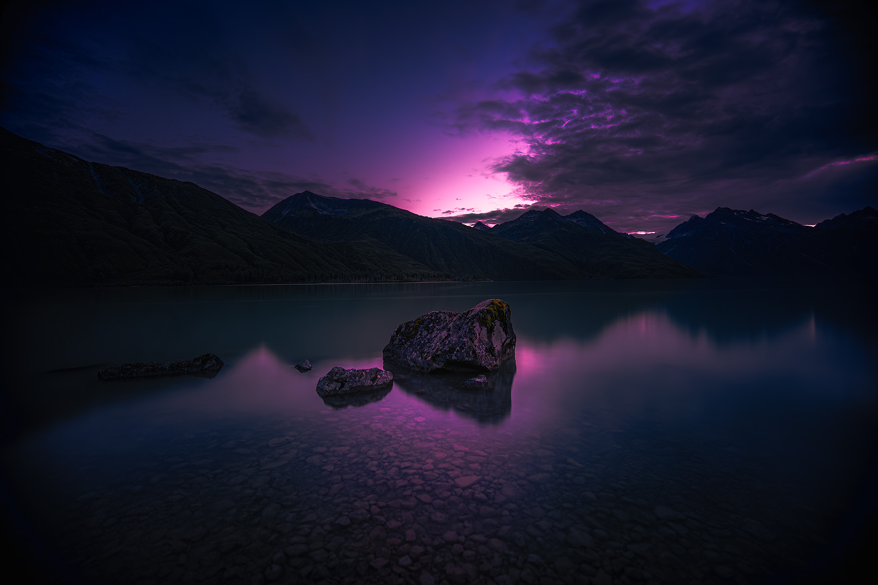 A long exposure captures the sunset's last light over Crescent Lake in Lake Clark National Park, with perfect reflections on the still water.