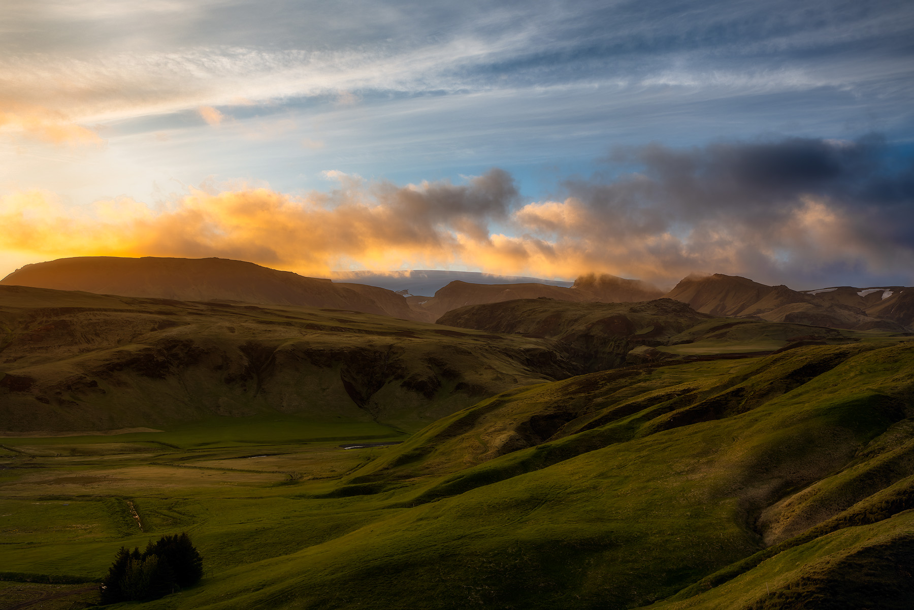 sunset in Iceland basks the rolling landscape and clouds with vibrant color.