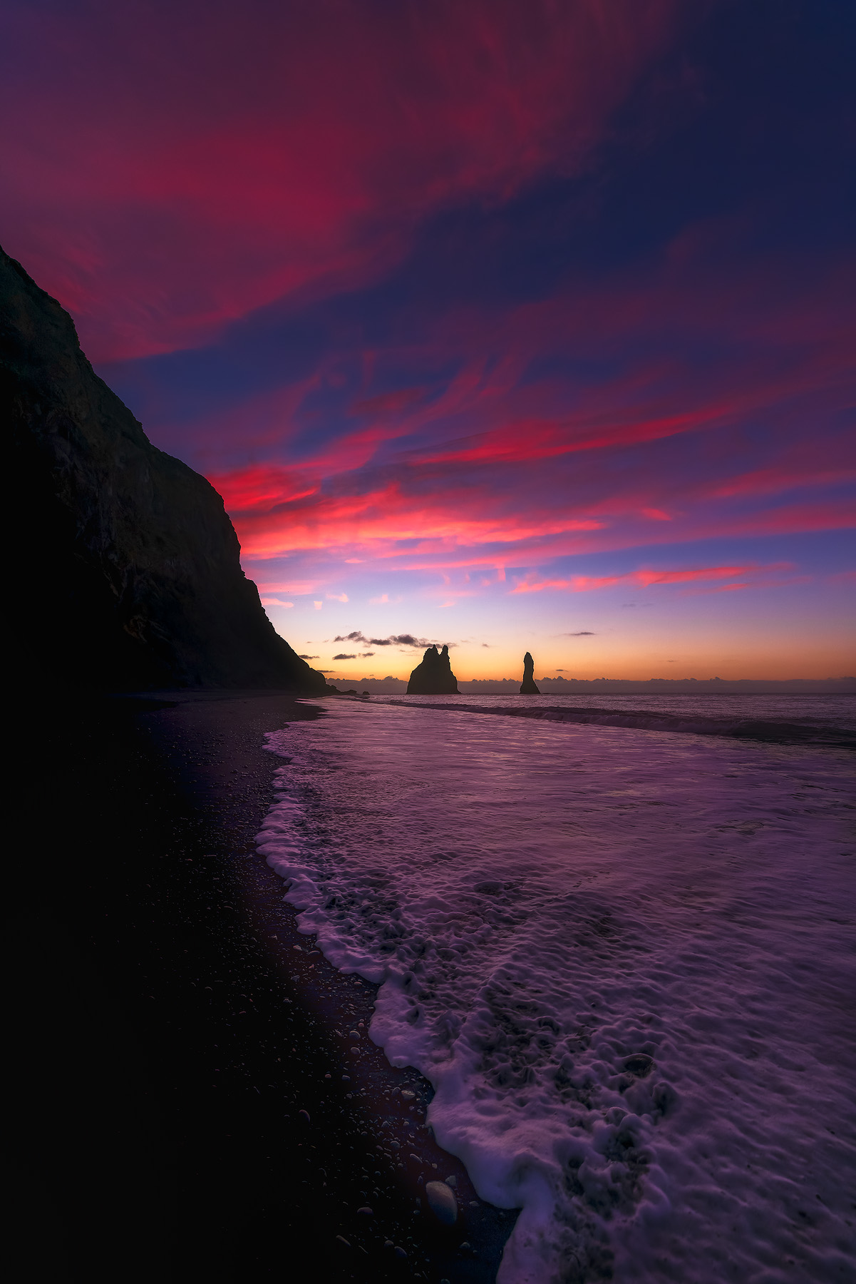 sunrise over sea stacks on the black sand beach of Vik Iceland and the basalt rock formations.