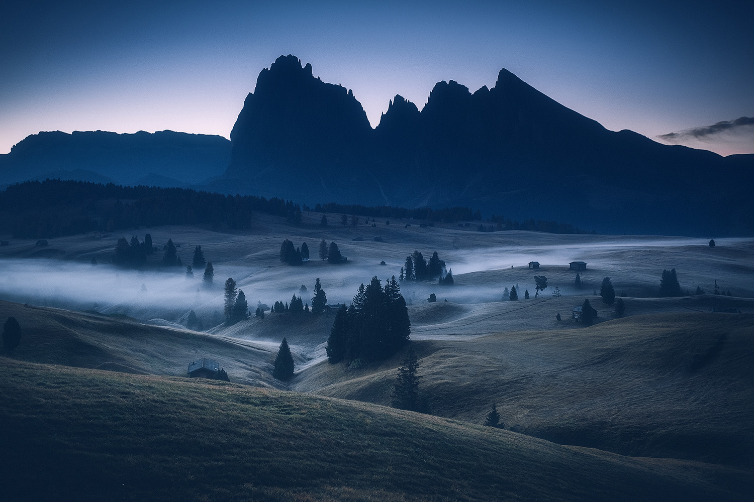 Alpe di Siusi blue hour with fog and silhouetted Italian Dolomites Odle peaks October autumn photography