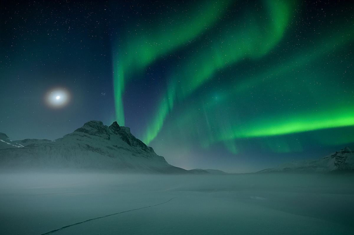 Aurora borealis over snow-covered Arctic mountains in Northern Nordland, Norway
