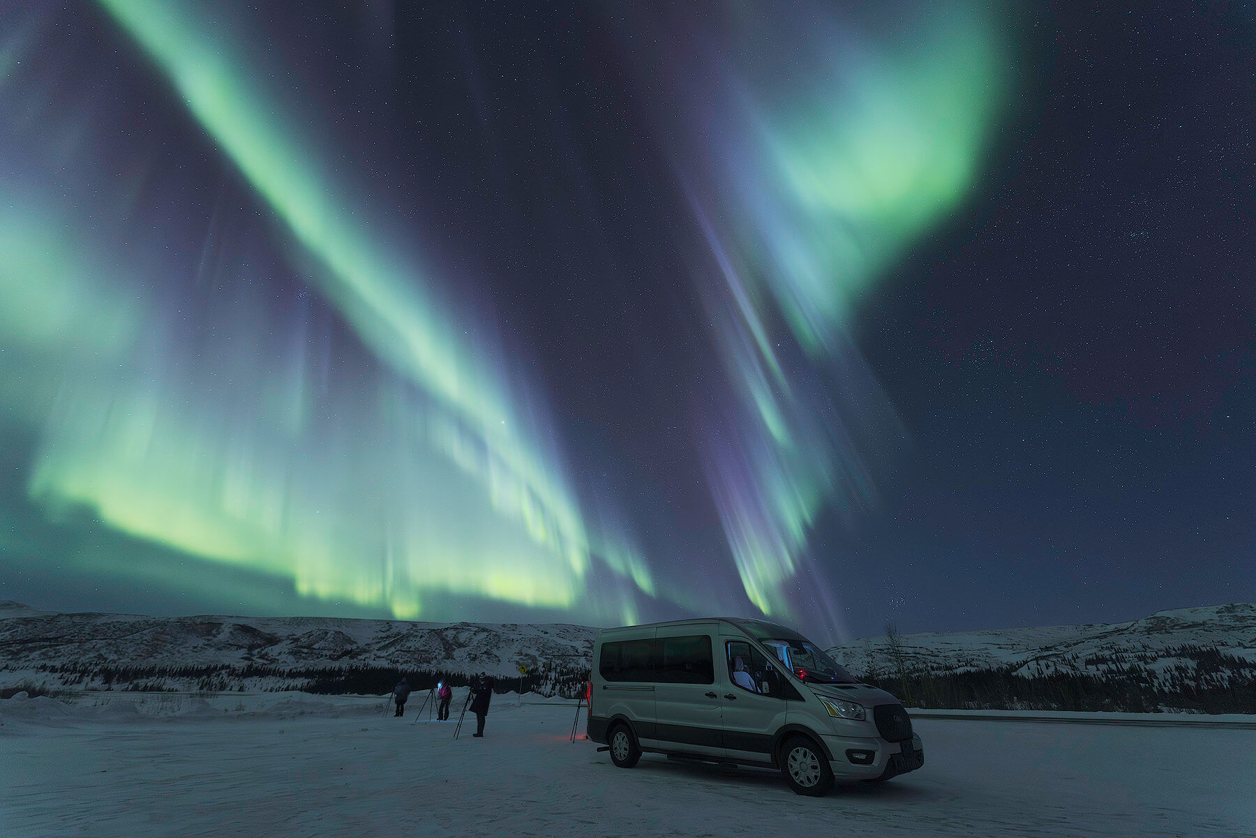 Workshop photographers and van under a bright aurora on the spring aurora photography workshop in Alaska