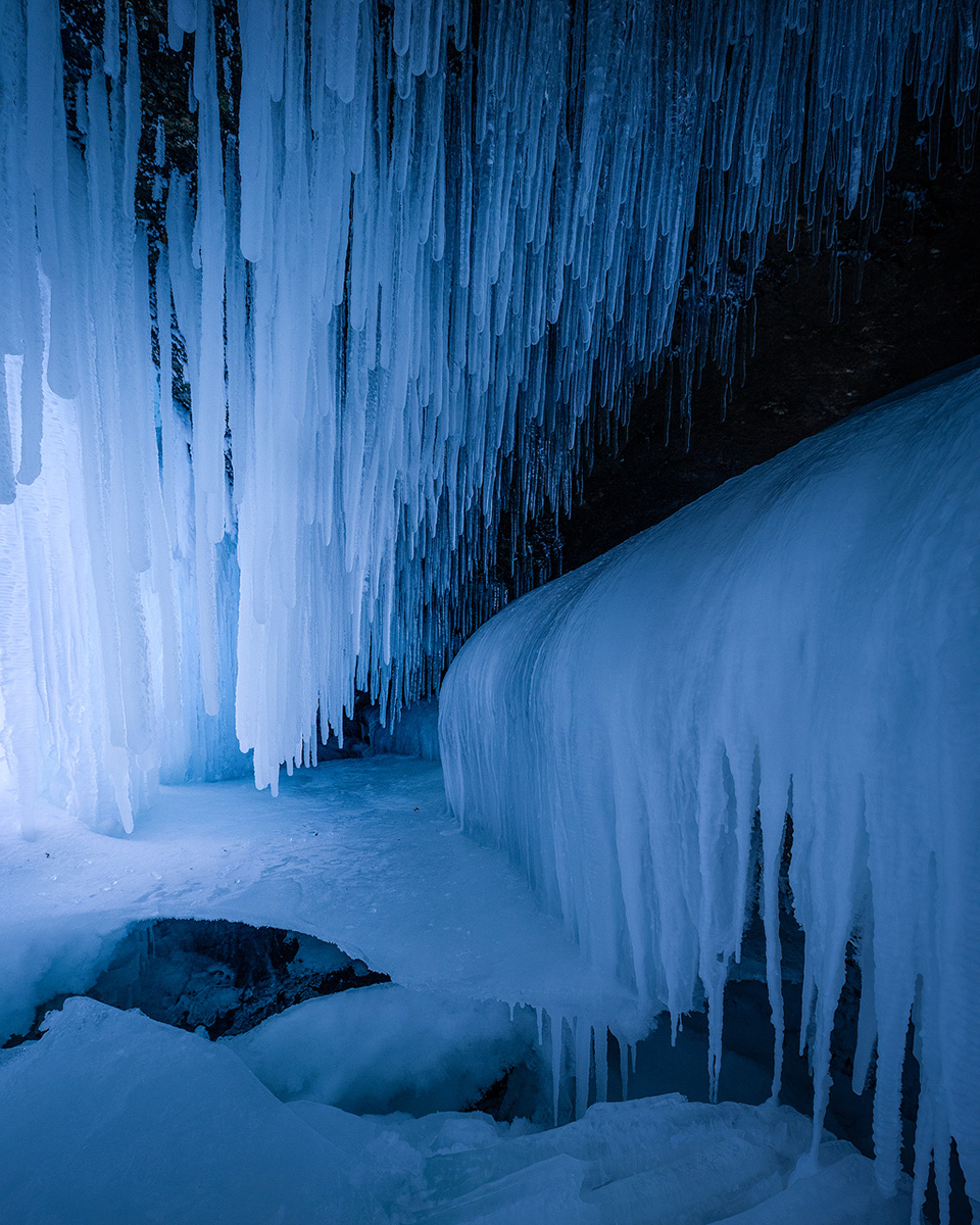 Blue ice cave with icicle formations in Northern Norway