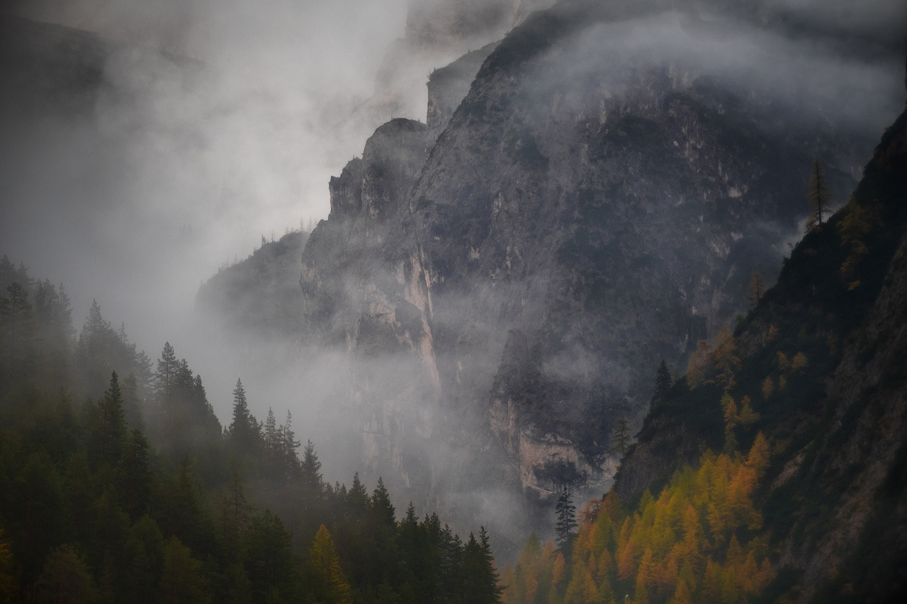 Italian Dolomites cliff face with autumn fog and golden forest October landscape photography
