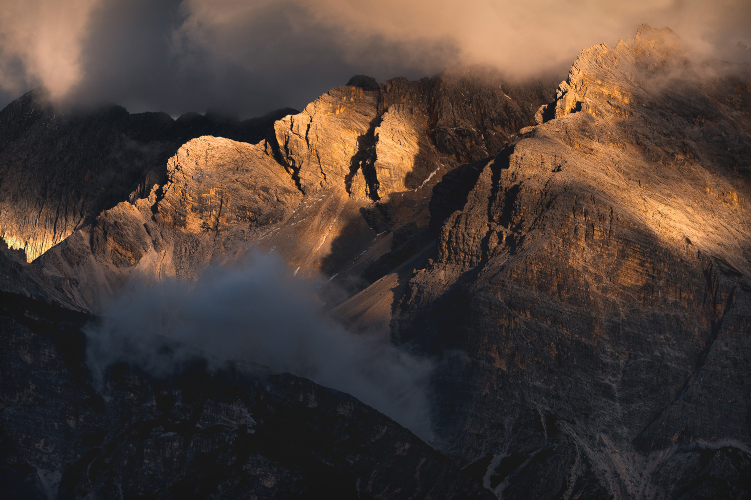 Dramatic sunset light on Italian Dolomites peaks with fog in valleys October autumn landscape photography