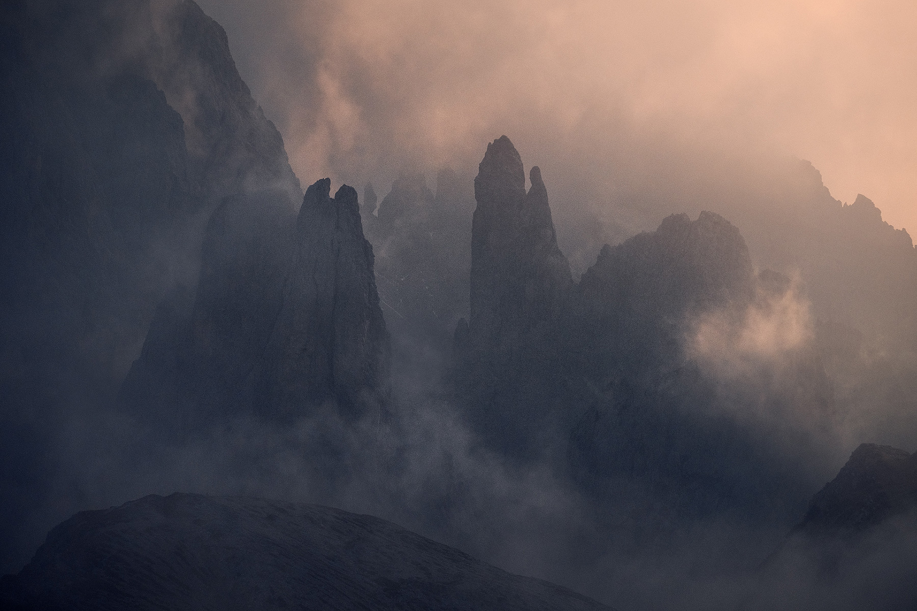 Silhouetted Italian Dolomites peaks in fog at dusk near Val Gardena October autumn photography