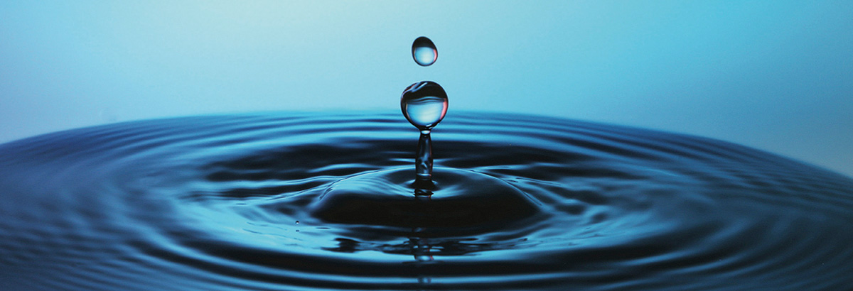 Water droplet frozen in mid-air by a fast shutter speed with concentric ripples radiating from the impact point demonstrating motion freeze technique