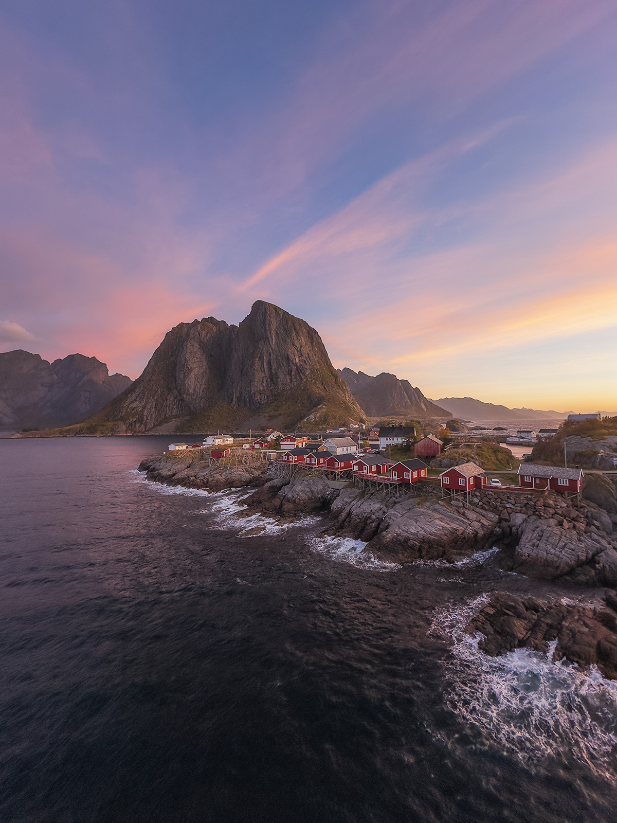 Sunrise over red fisherman cabins of Hamnoy with mountain in background