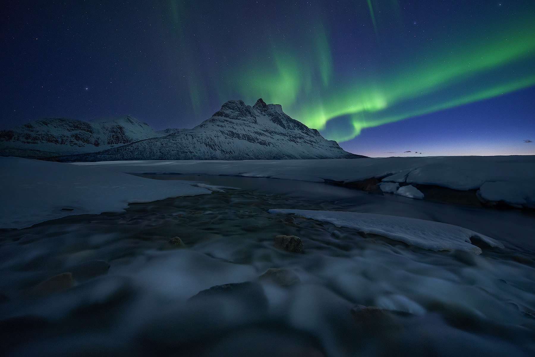 Northern lights over the Lofoten coast with waves washing over rocks on a winter night, Lofoten winter photography workshop in Norway
