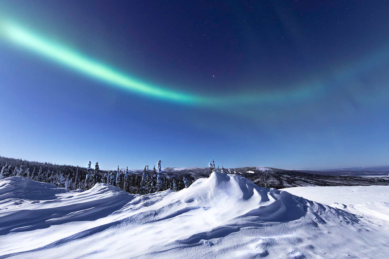 Sweeping aurora arc over snow drifts and boreal forest captured during the Spring 2026 Northern Lights Workshop in Alaska