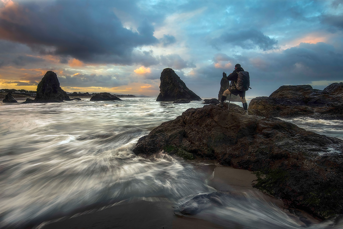 Michael Schultz photographing the Oregon coast at sunset with long exposure waves and sea stacks.