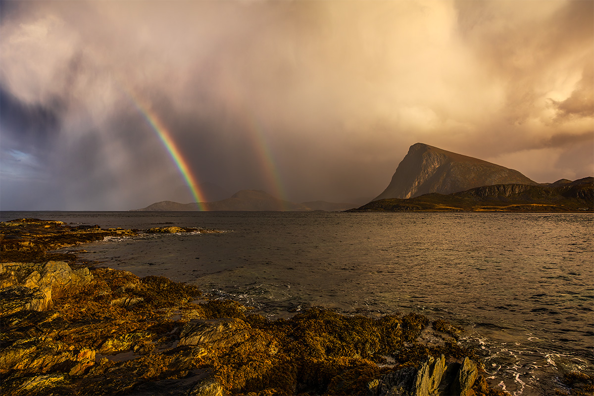 Shifting weather in the Lofoten Islands presents a double rainbow while sun tries to break through clouds
