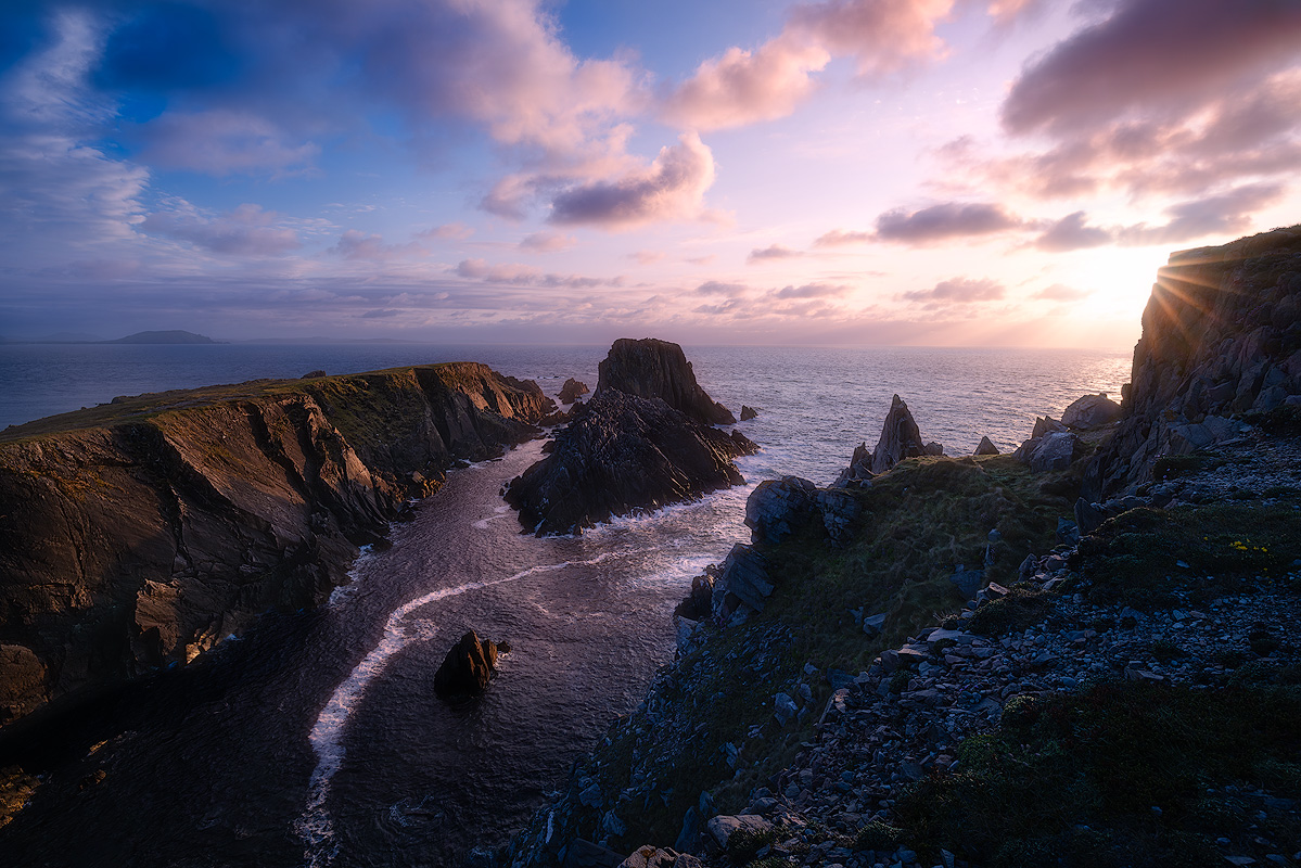 Dramatic coastal cliff landscape at sunset with sea stacks and sunburst demonstrating the rewards of consistent photography habits and dedication to the craft