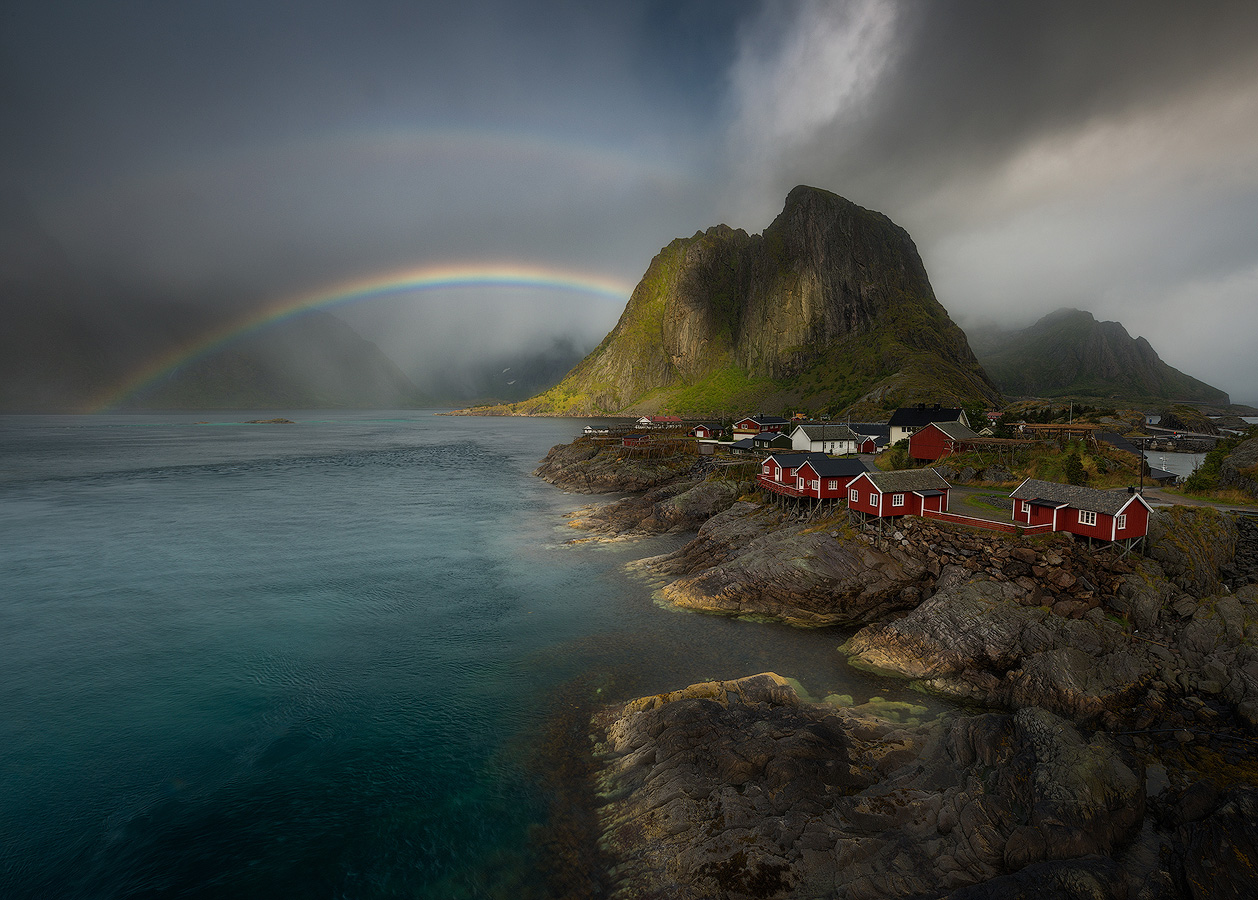 Rainbow over red rorbuer fishing cabins at Reine and Hamnøy in the Lofoten Islands, Norway