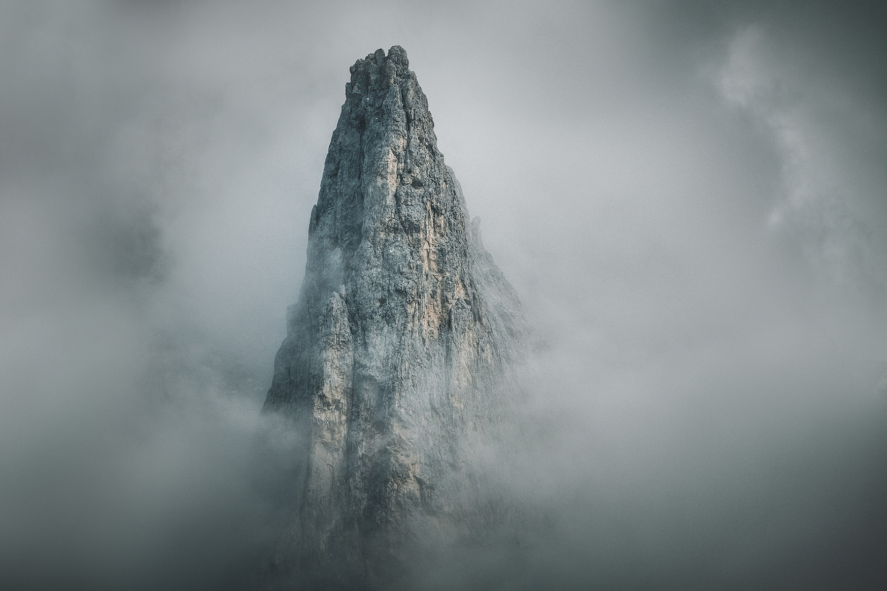 Single Italian Dolomites spire emerging from heavy fog near Cadini di Misurina October photography