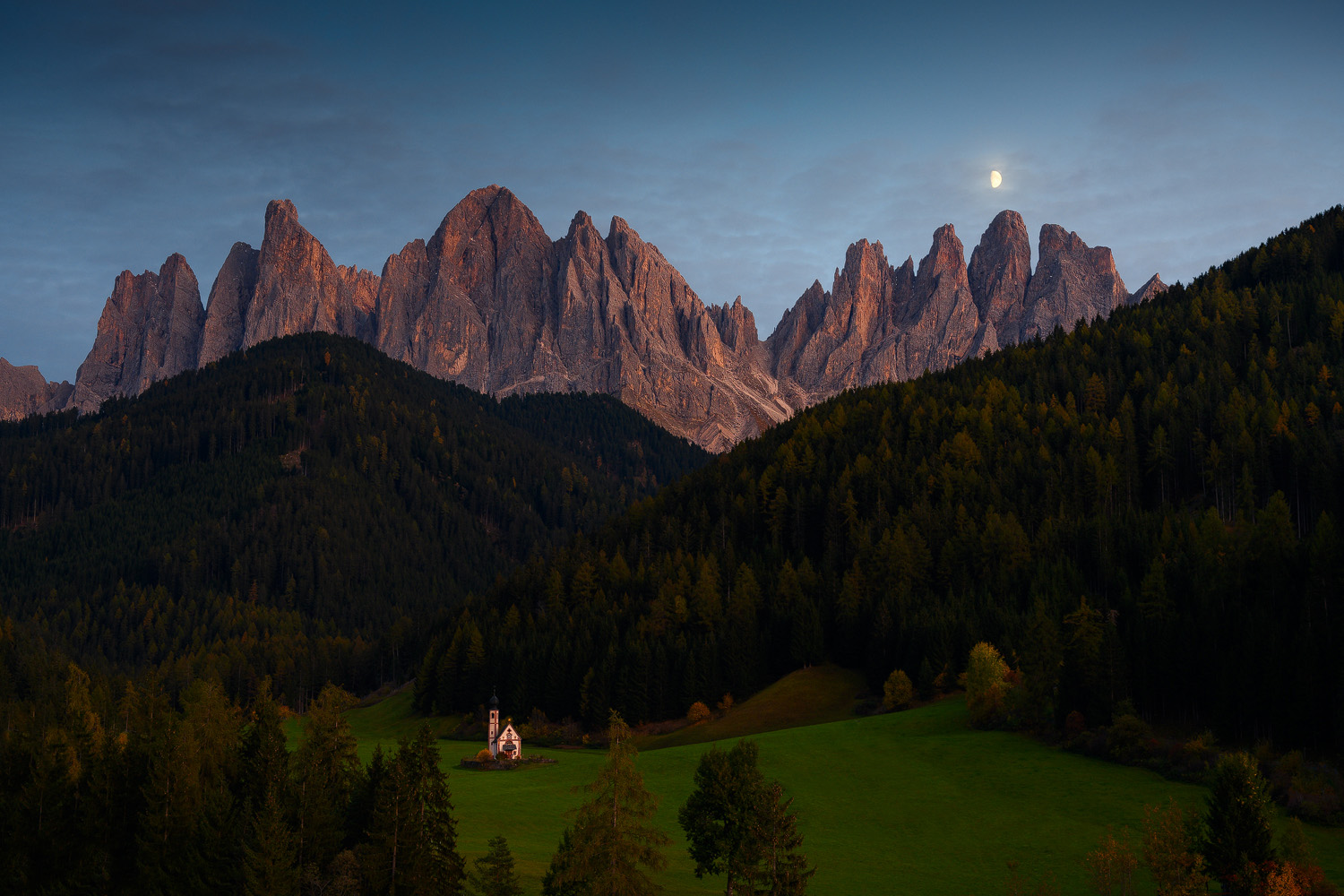 Alpenglow on Odle peaks with moon at dusk in Val di Funes Italian Dolomites October photography