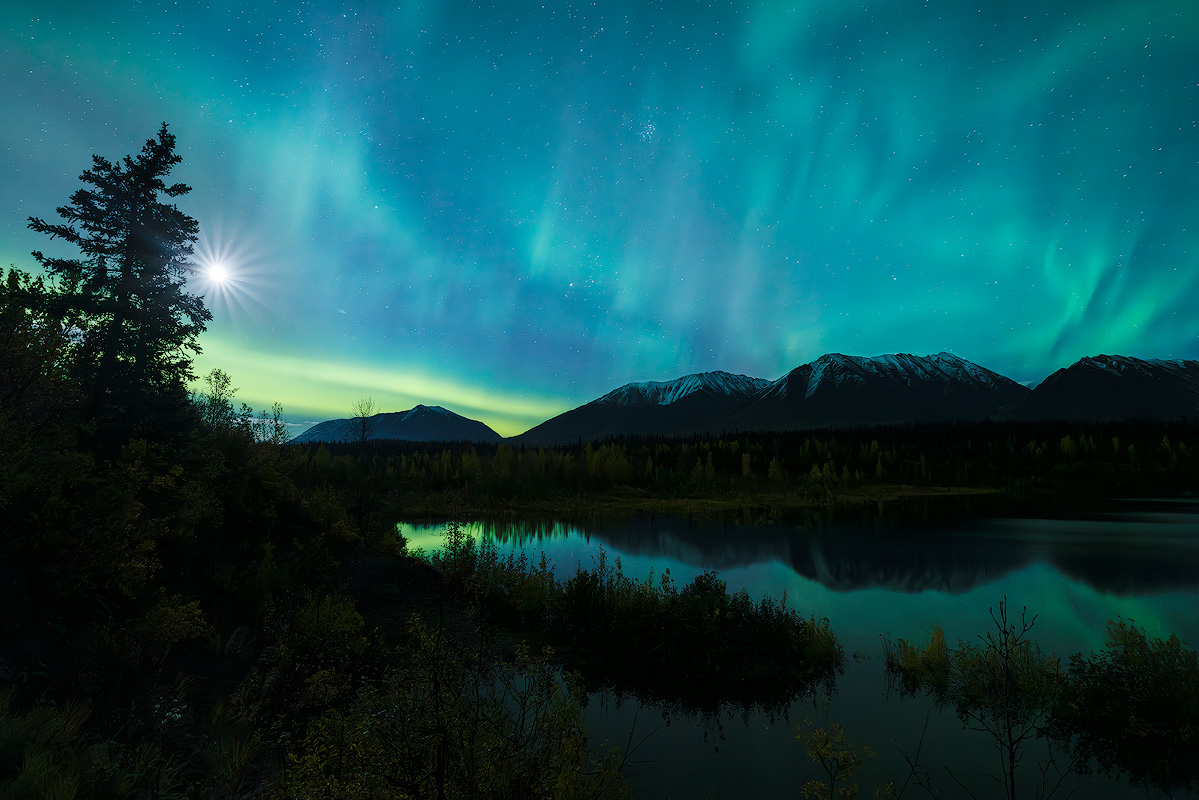 Wide angle astrophotography showing northern lights over dramatic landscape demonstrating night sky photography with short focal length