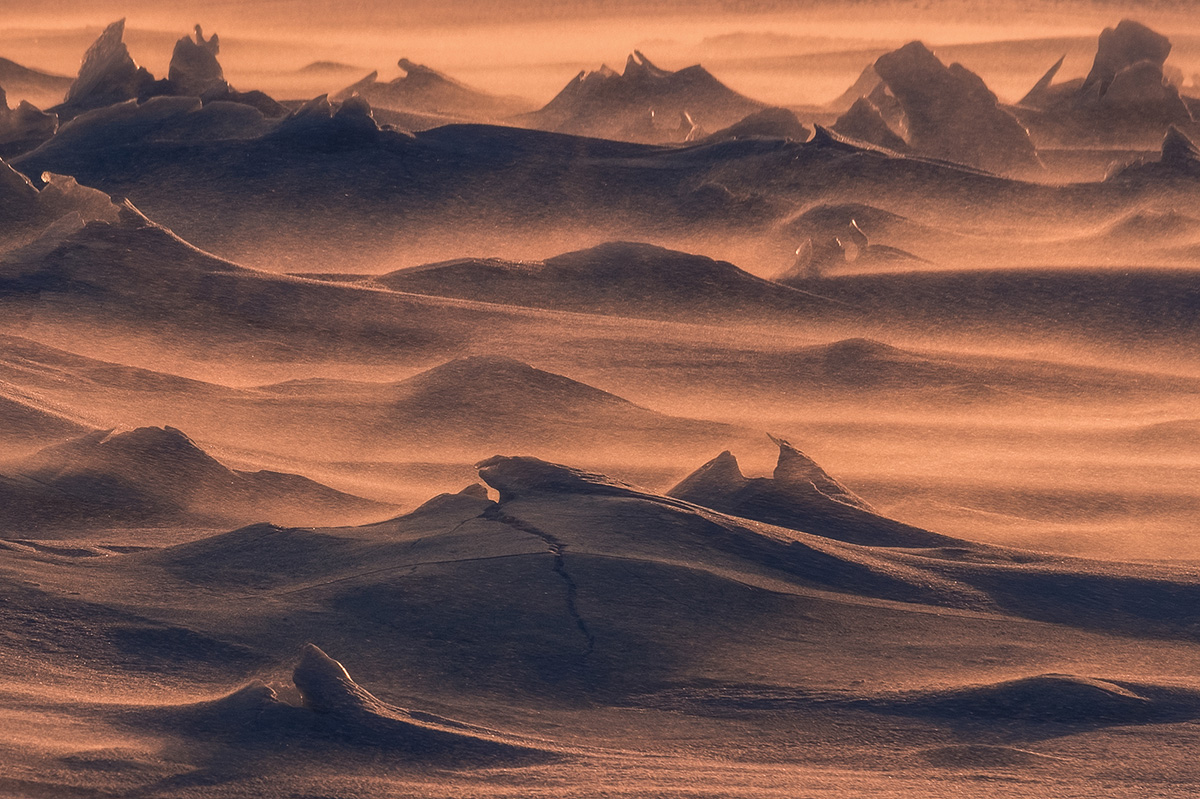 Golden sunset light on windswept snow and ice formations in Arctic Norway